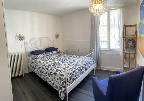 een slaapkamer met een bed en twee blauwe stoelen bij Badehotel Harmonien in Ærøskøbing
