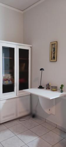 a white room with a desk and a window at Daphne's apartment in Kavala