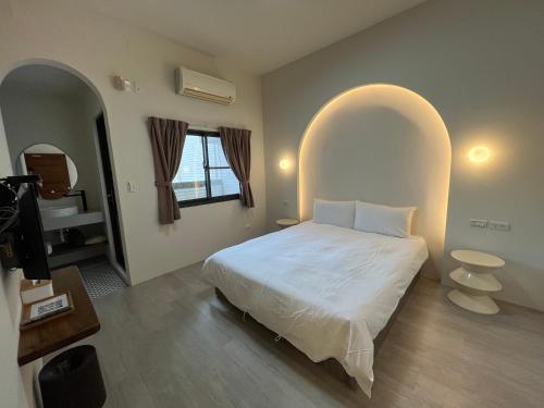 ein Schlafzimmer mit einem weißen Bett und einem Bogenfenster in der Unterkunft Big Nose Inn in Altstadt von Hengchun