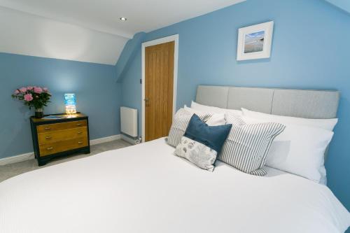 a bedroom with a large white bed with blue walls at Cae Coch in Newborough