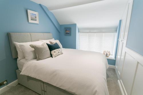a bedroom with a white bed with blue walls at Cae Coch in Newborough