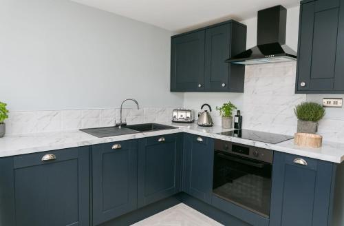 a kitchen with navy blue cabinets and a sink at Cae Coch in Newborough