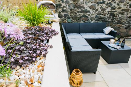 a patio with a couch and a table and flowers at Cae Coch in Newborough
