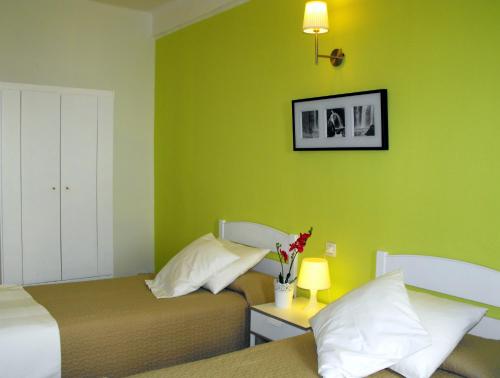 a bedroom with two beds and a green wall at Hostal Santa Catalina in Seville