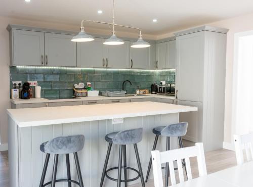 a kitchen with white cabinets and bar stools at Stylish 4 Bed, newly renovated home in Nottingham in Nottingham