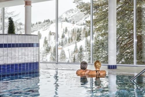 Ein Mann und eine Frau sitzen im Pool in der Unterkunft Hotel Römerhof Superior in Obertauern