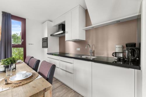 a kitchen with white cabinets and a wooden table at Vakantiepark Hof van Zeeland in Heinkensand