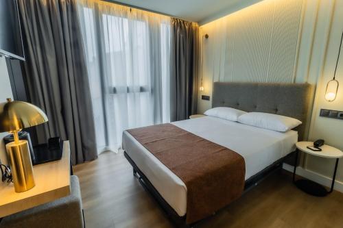 a hotel room with a bed and a large window at HOTEL CORONA DE PADRÓN in Padrón