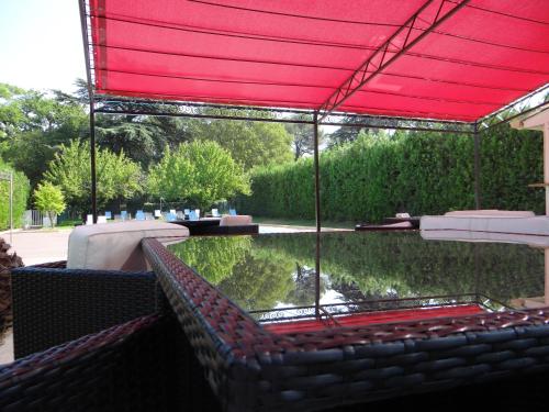 a patio with a red canopy over a pond at Domaine Du Val De Cèze in Bagnols-sur-Cèze