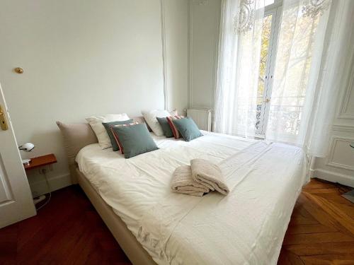 un grand lit blanc dans une chambre avec une fenêtre dans l'établissement l'appartement Malesherbes, à Paris