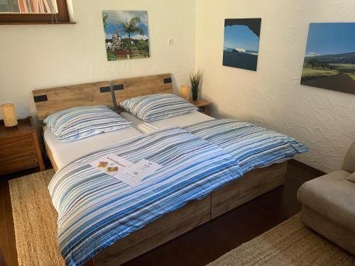 ein Bett mit einer blau-weißen gestreiften Bettdecke in einem Schlafzimmer in der Unterkunft Bauernhof - Auszeit mal anders in Seckach