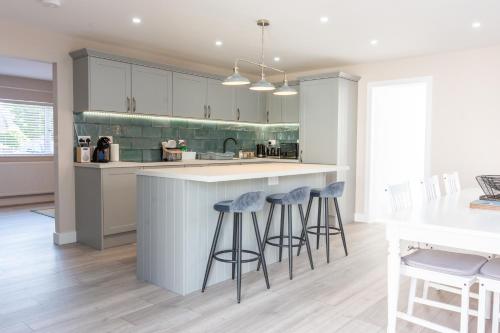 a kitchen with white cabinets and bar stools at Stylish 4 Bed, newly renovated home in Nottingham in Nottingham