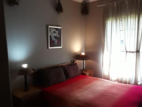 a bedroom with a red bed and a window at Emerald Hill Cottage in Mount Pleasant