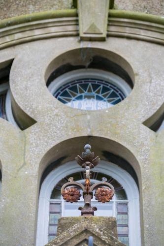 a cross on the side of a building with windows at Cribinau in Aberffraw