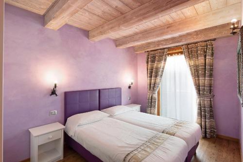 een paarse slaapkamer met een bed en een raam bij Chalet Picchio Bilocale in Livigno