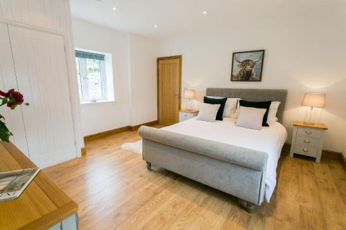 a bedroom with a white bed and a couch at Carrog Barn in Bodorgan