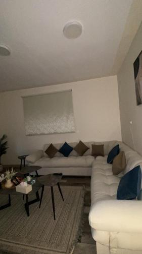 a living room with a white couch and blue pillows at جاذر إن in Ad Dawādimī