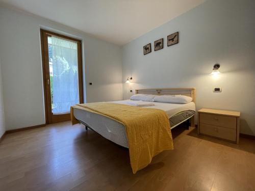 a bedroom with a bed with a yellow blanket on it at Residence Valentino in Pinzolo