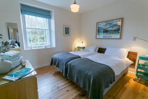 a bedroom with two beds and a desk and a window at Coron in Aberffraw