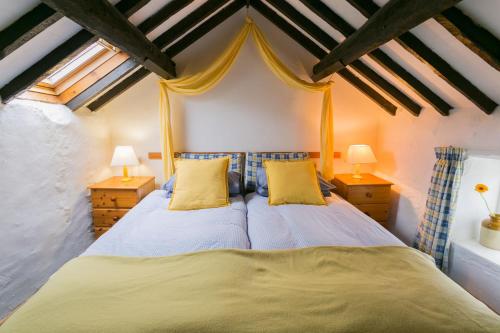 a bedroom with two beds with yellow pillows at Cyndal Bach in Rhoscolyn