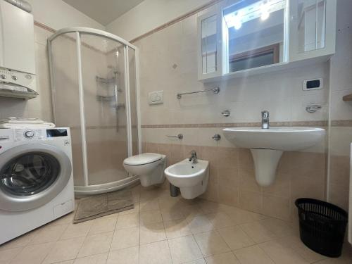 a bathroom with a toilet sink and a washing machine at Residence Valentino in Pinzolo