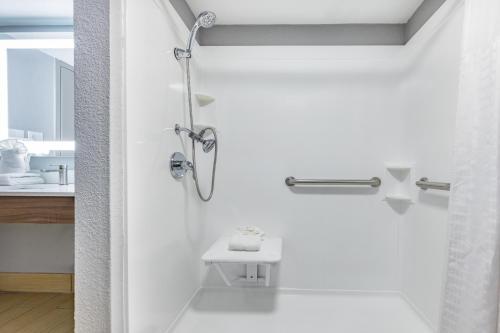 a white bathroom with a shower and a sink at Hawthorn Extended Stay by Wyndham Wichita Airport in Wichita