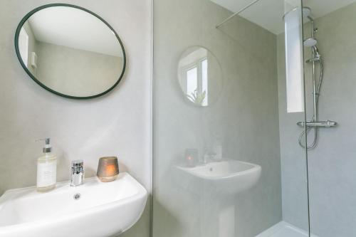 a white bathroom with a sink and a mirror at Cil Haul in Llanfaelog