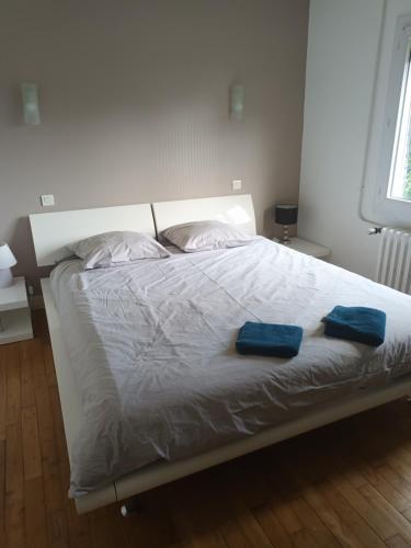 uma cama branca com duas toalhas azuis em Charmante maison em Dinard