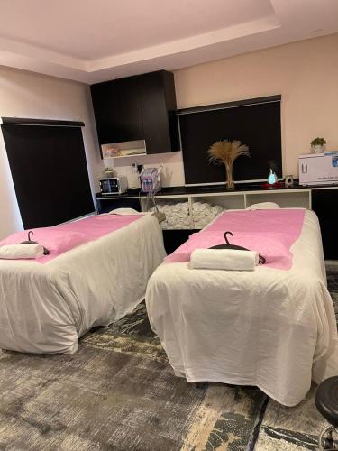 a room with two beds with pink and white sheets at YANNA APARTMENT BY KHALIQUES in Abuja