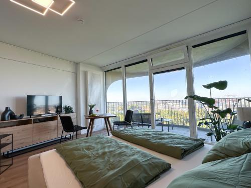 a living room with a couch and a tv and windows at Helles Apartment mit tollem Blick über Augsburg in Augsburg
