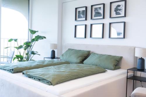 a white bed with green pillows on top of it at Helles Apartment mit tollem Blick über Augsburg in Augsburg