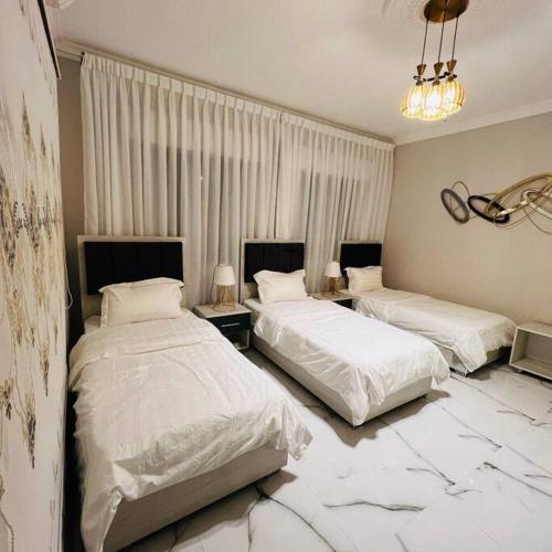 two beds in a hotel room with marble floors at Luxury 4-bedrooms apartment in Aqaba