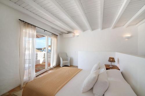 a white bedroom with a bed and a large window at Casa de Benafim 51 in Benafim