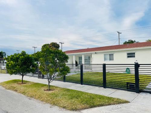 una casa con una valla negra y dos árboles en Nuvole Guest Suite, en Miami