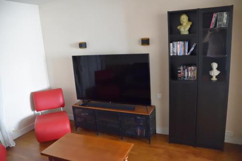 salon z telewizorem i 2 czerwonymi krzesłami w obiekcie Le clos argoat w mieście Pontivy