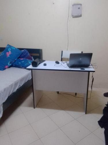 un escritorio con un ordenador portátil junto a una cama en Wendani en Nairobi