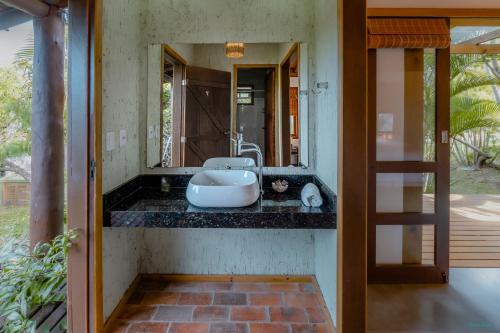 a bathroom with a sink and a mirror at Pousada Watu Kerere in Praia do Rosa