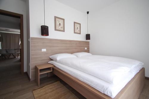 a bedroom with a large white bed with a wooden headboard at Apartments Villa Rivarella in Novigrad Istria