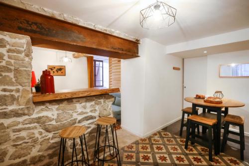 Cette chambre dispose d'un mur en pierre, d'une table et de tabourets. dans l'établissement Studio du Charme Médiéval ConciergerieDameCarcas, à Carcassonne