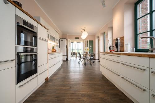 a kitchen with white cabinets and a wooden floor at Ferienhaus Landurlaub mit Kamin in Schwarz