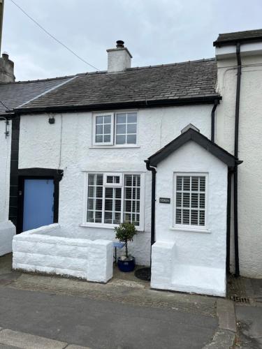 a white house with a blue door and aphalt at SEREN cottage by the sea in Llangadwaladr
