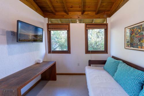 a living room with a couch and two windows at Pousada Watu Kerere in Praia do Rosa