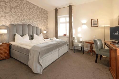 a bedroom with a large bed and a desk and a computer at Bernstein Schlosshotel Ballenstedt in Ballenstedt