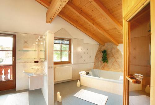 baño grande con bañera y lavamanos en Landhaus Kostenzer mit Sauna, en Fügen