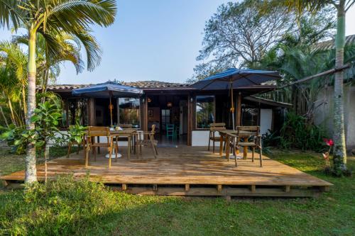 a wooden deck with tables and chairs and umbrellas at Pousada Watu Kerere in Praia do Rosa