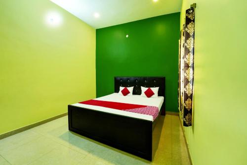 a green bedroom with a bed with red sheets at OYO Flagship Raj Munmun Hotel in Dhanbād