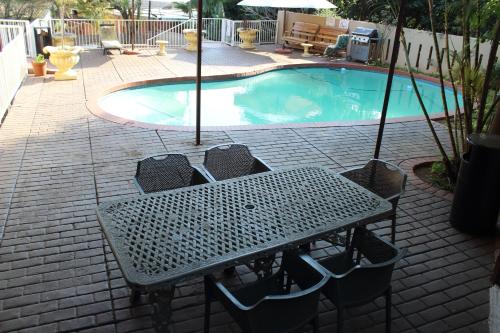 a table and chairs in front of a swimming pool at Purple Olive Guest House in Pretoria