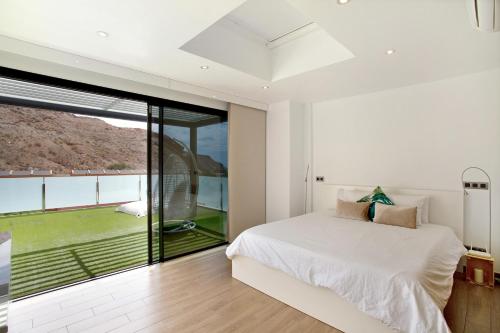 a bedroom with a white bed and a large window at Villa Tauro 31 in Mogán