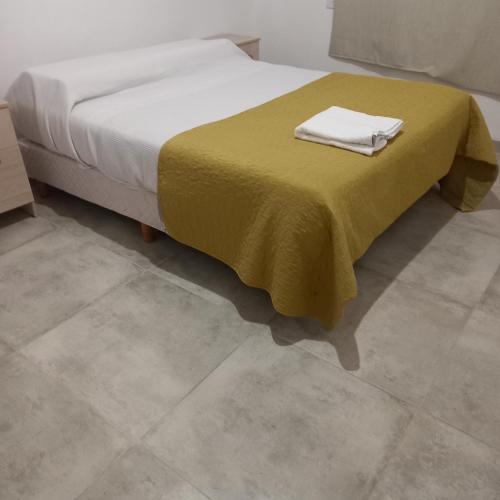 Un dormitorio con una cama con una manta amarilla. en Cabañas Plottier-Neuquén en Plottier