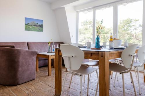 uma sala de jantar com uma mesa de madeira e cadeiras brancas em DER STÖRTEBEKER - "Apartment Born" Apartments hinter den Dünen em Dierhagen